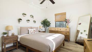 A bedroom with a bed, bedside tables, a dresser, a ceiling fan, and wall-mounted planters.