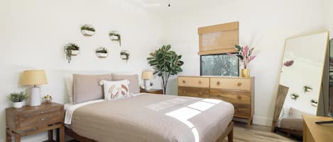 A bedroom with a bed, bedside tables, a dresser, a ceiling fan, and wall-mounted planters.
