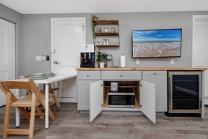 A compact kitchen with a built-in microwave, a coffee machine, and a refrigerator.