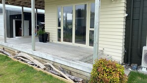 Een huis met een overdekte veranda, schuiframen en een kleine tuin.