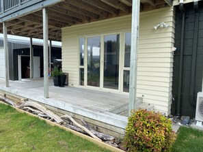A house with a covered porch, sliding glass doors, and a small garden area. - Whitianga downstairs flat with car & boat parking close to beach (Whitianga)
