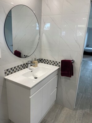 A bathroom with a white sink, a mirror, and a tiled backsplash. - Whitianga downstairs flat with car & boat parking close to beach (Whitianga)
