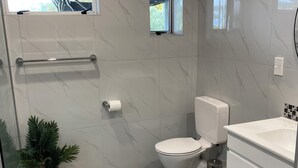 Een badkamer met toilet, wastafel en een klein raam.