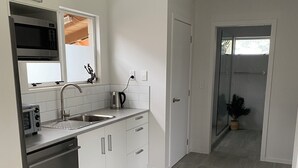Een moderne keuken met witte kasten, roestvrijstalen apparatuur en een grijze betegelde vloer.