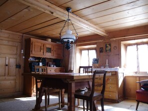 A wooden cabin interior with a dining table, chairs, a hanging light fixture, and wooden cabinets. - Ferienhaus Altes Walserhaus, Brün, (Valendas-Brün), 22004B by Interhome (Valendas)