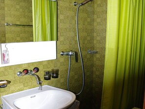 Ein Badezimmer mit einem weißen Waschbecken, einem Spiegel, einer Dusche und grünen Vorhängen.
