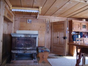 A wooden interior with a large stove, a door, and a table with chairs. - Ferienhaus Altes Walserhaus, Brün, (Valendas-Brün), 22004B by Interhome (Valendas)