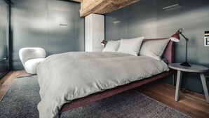 Ein modernes Schlafzimmer mit einem Bett, einem Sessel, einem Nachttisch und einer Lampe.