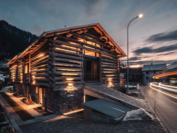 A log cabin with a stone foundation, a wooden porch, and a bench.