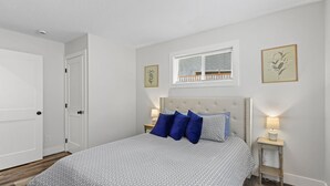 A bedroom with a bed, two bedside tables, a window with blinds, and a door. - 14-Acre Mountain Escape - Hot Tub + Fire Pit (Nehalem)