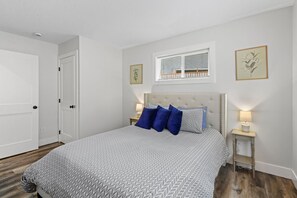 A bedroom with a bed, two bedside tables, a window with blinds, and a door. - 14-Acre Mountain Escape - Hot Tub + Fire Pit (Nehalem)