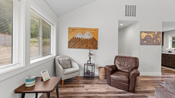 A modern living room with a brown leather sofa, a gray armchair, and a wooden coffee table. - 14-Acre Mountain Escape - Hot Tub + Fire Pit (Nehalem)