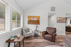 A modern living room with a brown leather sofa, a gray armchair, and a wooden coffee table. - 14-Acre Mountain Escape - Hot Tub + Fire Pit (Nehalem)