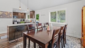 A modern kitchen with dark wooden cabinets, a white island, and pendant lighting. - 14-Acre Mountain Escape - Hot Tub + Fire Pit (Nehalem)
