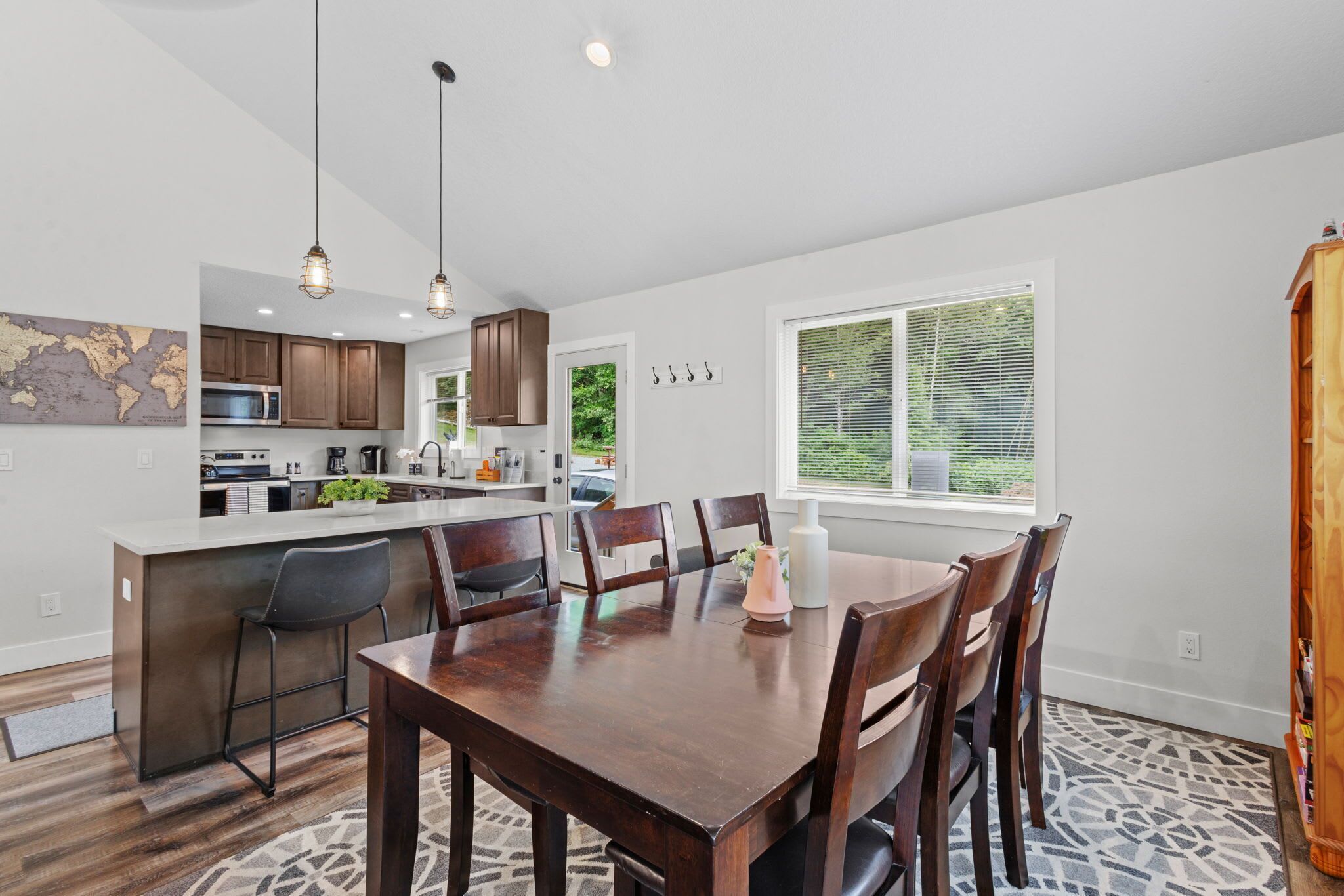 A modern kitchen with dark wooden cabinets, a white island, and pendant lighting. - 14-Acre Mountain Escape - Hot Tub + Fire Pit (Nehalem)
