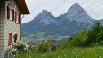 Ein Haus mit roten Fensterläden, einem geneigten Dach und Blick auf ein Gebirge.