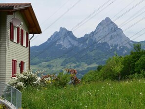 Une maison avec des volets rouges, un toit en pente et une vue sur une chaîne de montagnes.