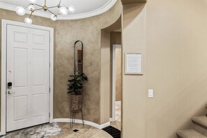 A hallway with a white door, a mirror, a wicker basket with a plant, and a framed notice on the wall. - Grayhawk Townhome in Northern Scottsdale (Scottsdale)