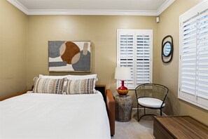 A bedroom with a bed, a chair, a lamp, a painting, and a window with blinds. - Grayhawk Townhome in Northern Scottsdale (Scottsdale)