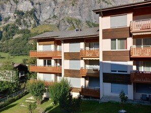 A multi-story hotel with balconies, a mountain backdrop, and a well-maintained lawn. - Gstein E3 # 4-bed apartment, Bad, WC 4-bed apartment, Bad, WC by Interhome (Leukerbad)