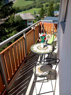A balcony with a small table, a chair, and a clock. - Gstein E3 # 4-bed apartment, Bad, WC 4-bed apartment, Bad, WC by Interhome (Leukerbad)