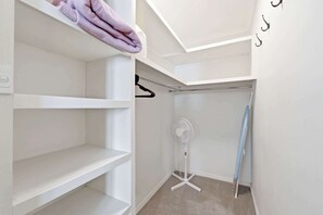 Un vestidor con estantes blancos, una barra para colgar ropa y un ventilador de techo.