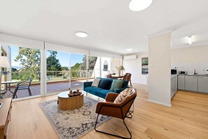 Ein modernes Wohnzimmer mit Balkon, einer Couch, einem Couchtisch und einem Essbereich.
