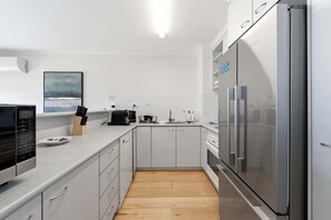 Eine moderne Küche mit weißen Schränken, einem Edelstahl-Kühlschrank und einer Mikrowelle.