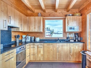 Eine moderne Küche mit Holzausbau, einem Backofen, einer Mikrowelle und einem Fenster mit Blick auf Bäume.