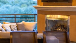 Un espace extérieur accueillant, doté d’une cheminée, de sièges confortables et offrant une vue sur le paysage.