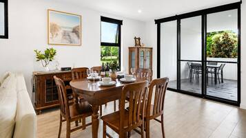 A dining area with a wooden table and chairs, a cabinet with glass doors, and a painting on the wall.