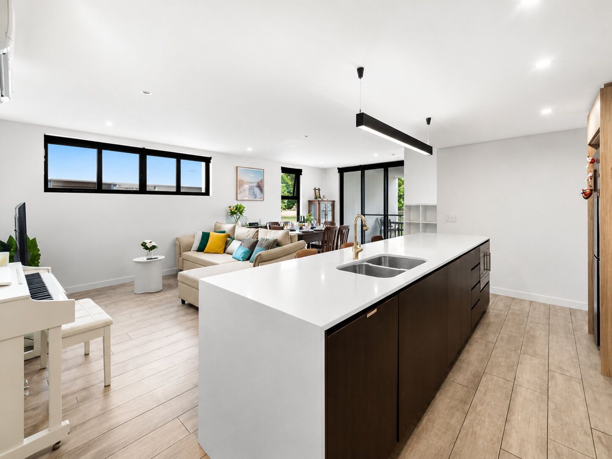 A modern kitchen with a central island, a dining area with a sofa, and a piano.