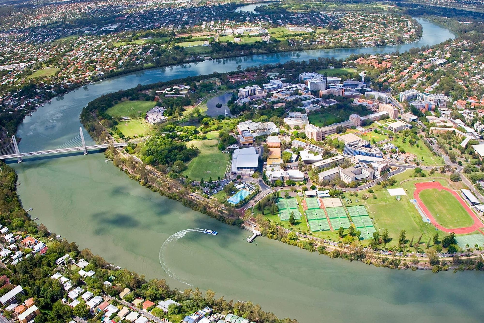 An aerial view of a campus with a river, buildings, and a bridge.