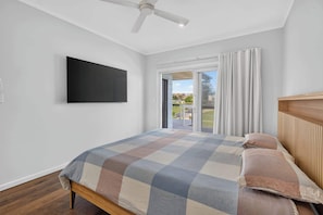 A bedroom with a bed, a ceiling fan, a TV mounted on the wall, and a sliding glass door leading to an outdoor area. - Beachside Family Escape 92 Newell Avenue Middleton Spacious 4-Bedroom Holiday Home Sleeps 10 one street from Middleton Beach (Middleton)