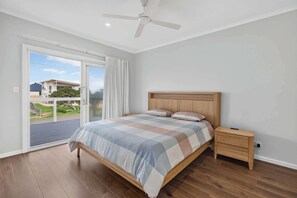 A bedroom with a bed, a nightstand, a ceiling fan, and a sliding glass door leading to an outdoor area. - Beachside Family Escape 92 Newell Avenue Middleton Spacious 4-Bedroom Holiday Home Sleeps 10 one street from Middleton Beach (Middleton)