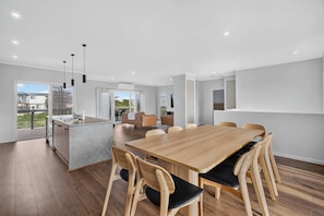 A modern interior with a dining area, kitchen, and a view of the outside. - Beachside Family Escape 92 Newell Avenue Middleton Spacious 4-Bedroom Holiday Home Sleeps 10 one street from Middleton Beach (Middleton)