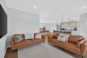 Ein modernes Wohnzimmer mit zwei Ledersofas, einem Essbereich und einer Küche mit Kochinsel.