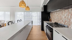 A modern kitchen with a central island, black cabinetry, and a patterned backsplash. - Stillwater - holiday home with a private jetty (Wellington East)