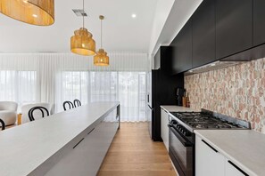 A modern kitchen with a central island, black cabinetry, and a patterned backsplash. - Stillwater - holiday home with a private jetty (Wellington East)