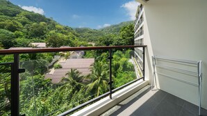 Uma varanda com vista para uma encosta verdejante e um edifício com telhado vermelho.