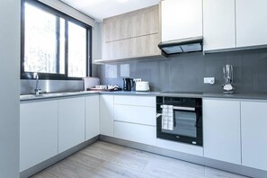 A modern kitchen with white cabinetry, a built-in oven, and a window providing natural light.