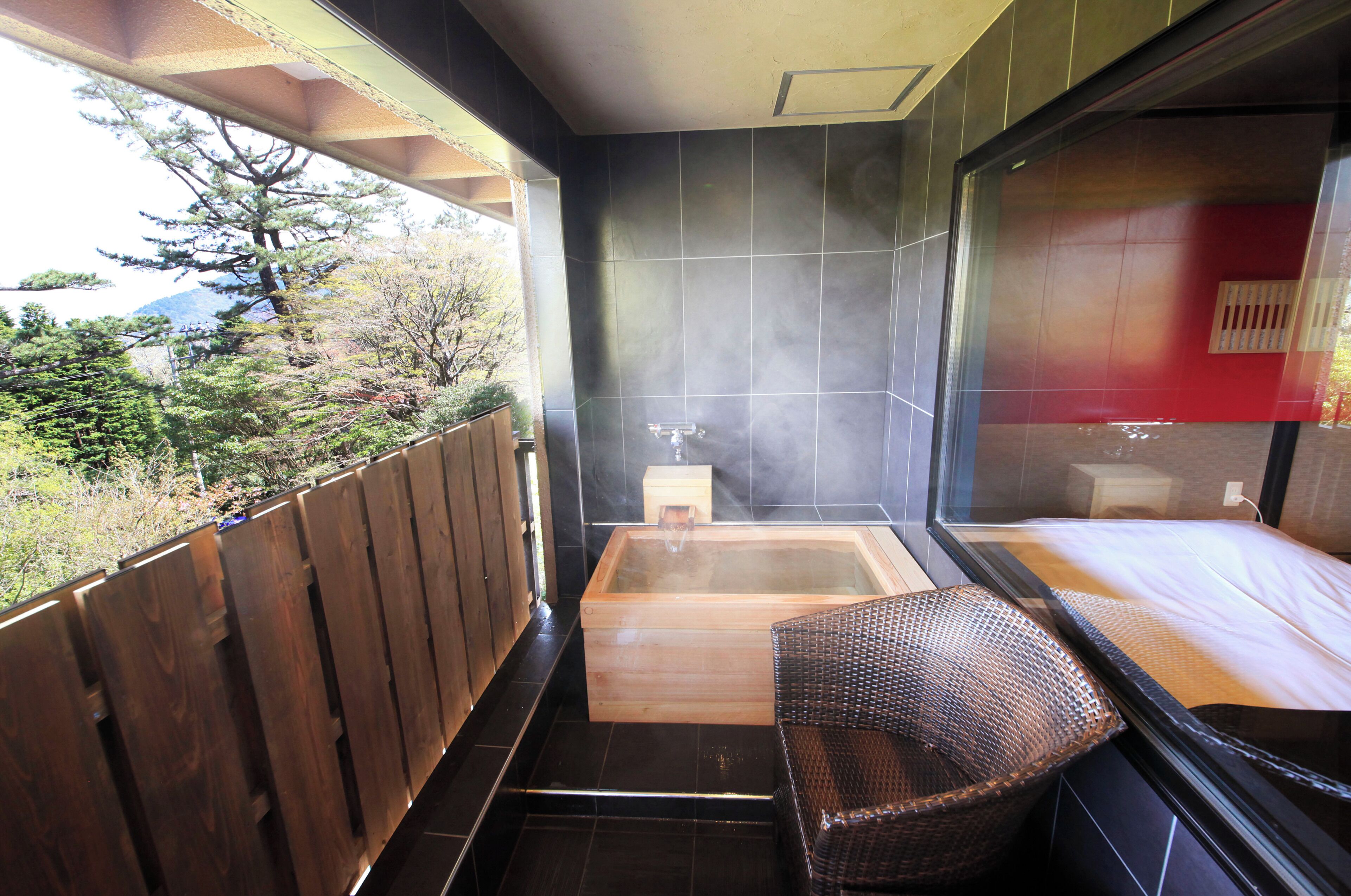 Un balcón con cerramiento de madera, un jacuzzi y una silla de mimbre.