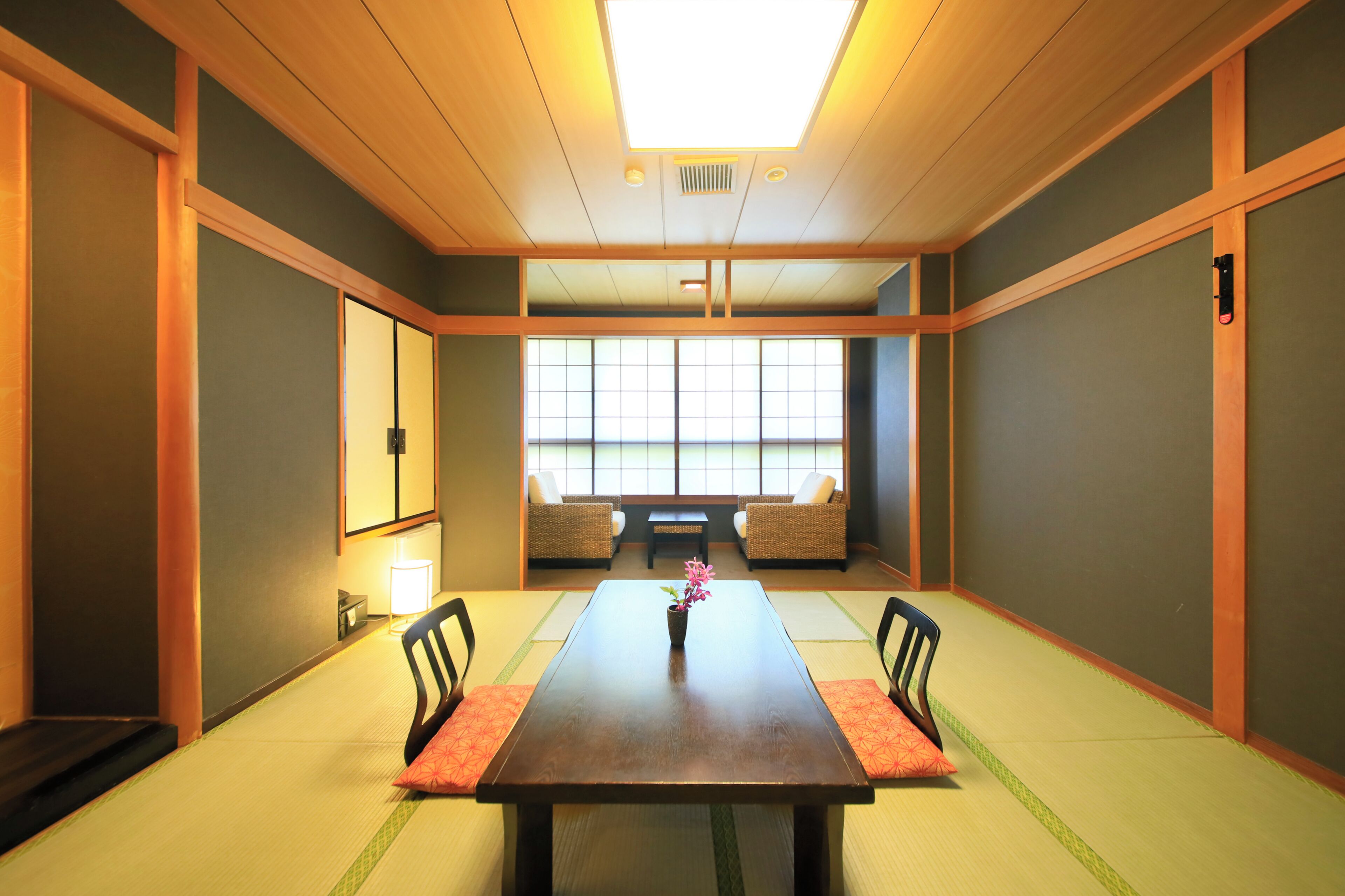 Una habitación tradicional japonesa con suelo de tatami, una mesa baja y dos sillas.