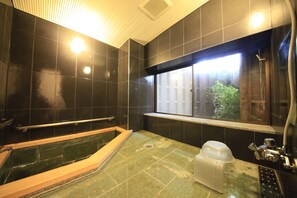 A bathroom with a bathtub, a window, and a shower area.