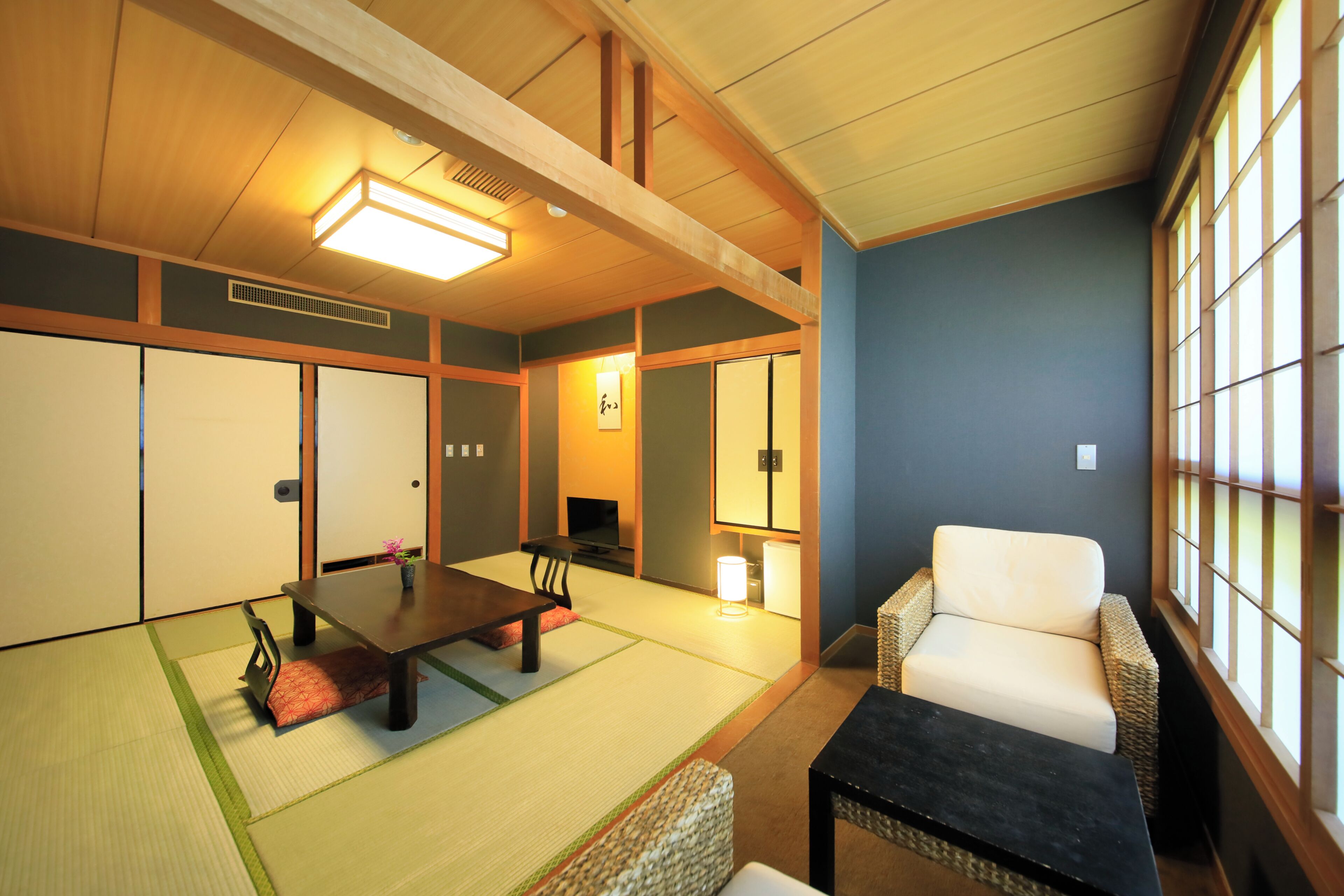 Una habitación de estilo japonés tradicional con suelo de tatami, una mesa baja, un sofá y puertas correderas.