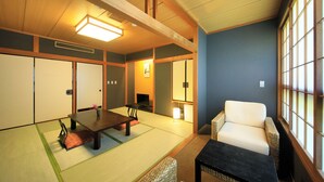 Une pièce de style japonais traditionnel, avec un sol recouvert de tatamis, une table basse, un canapé et des portes coulissantes.