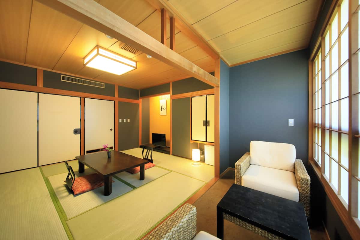 A traditional Japanese room with tatami flooring, a low table, a sofa, and sliding doors.