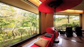 Una habitación con un ventanal grande, un paraguas rojo y un banco con almohadones.