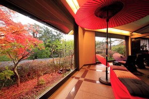 Una habitación con vistas a follaje otoñal, un paraguas rojo y un suelo a cuadros.