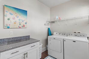 A laundry room with a granite countertop, a washing machine, a dryer, and a wall-mounted drying rack. - Steps2 Beach/Gulf Views/Heated Pool&Spa/Golf Cart (Destin)
